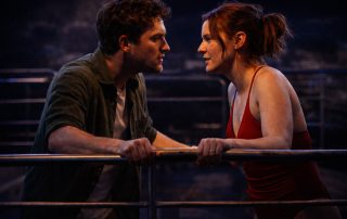 Two actors facing each other intensely on a dimly lit stage resembling a cruise setting, capturing emotional tension at Edinburgh Fringe theatre performance