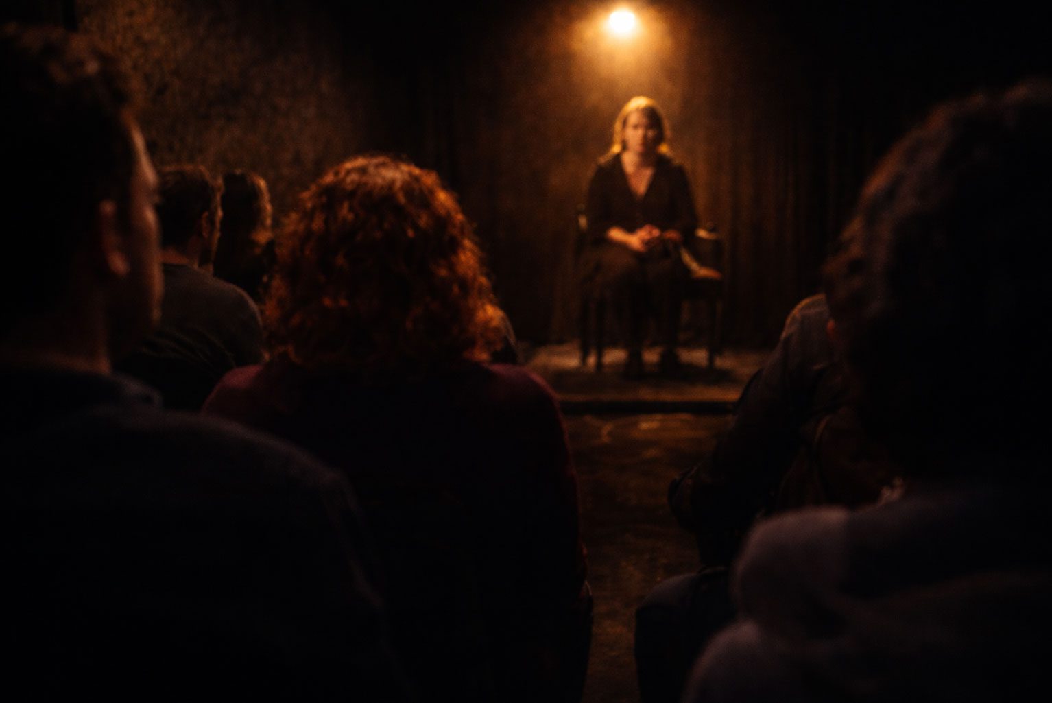 Intimate black box theatre performance with audience seated close to a performer under warm spotlight at Edinburgh Fringe Festival 2026