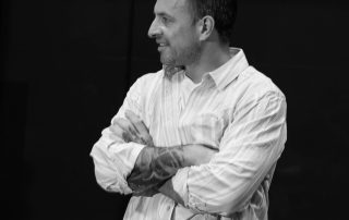 Male actor smiling during rehearsal break for Constellations, capturing candid moment inside theatre space before Fringe