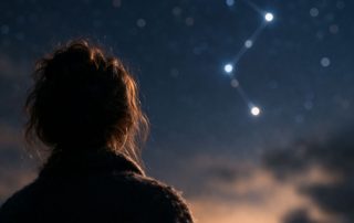 Silhouetted figure looking at star constellation representing choice and multiple possibilities in Constellations play